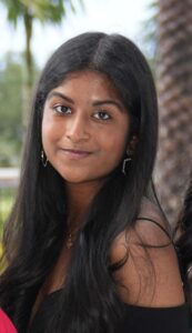Headshot of Karina Samuel standing in front of a blurred out palm tree