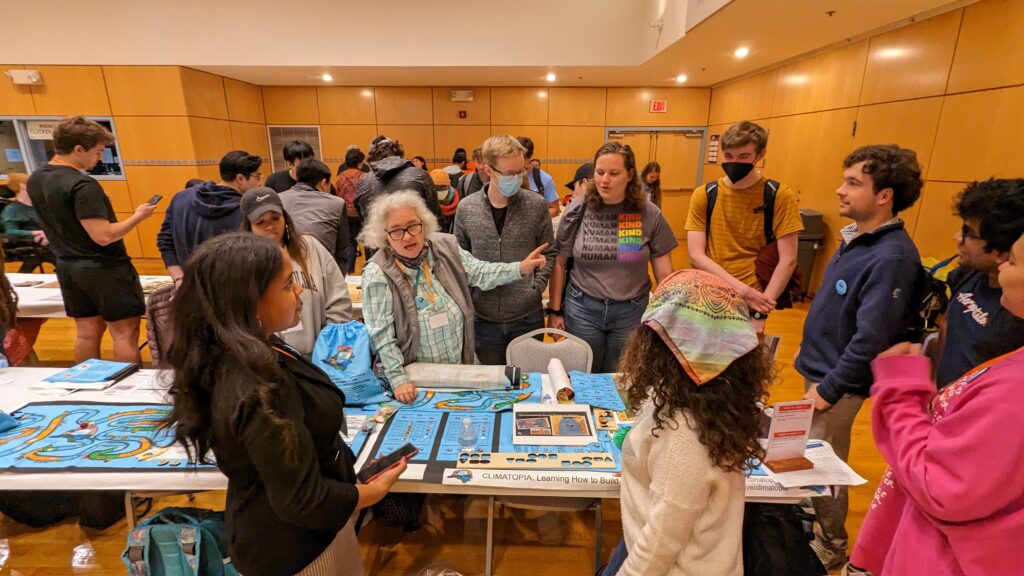group of individuals gathered around a table, and engaging in a discussion regarding climatopia at the 2023 Makerfest