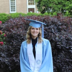 Julie Yates smiling on UNC campus with her Carolina blue graduation hat and wardrobe on 