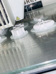 Various white game pieces in the 3D printer in the process of being made