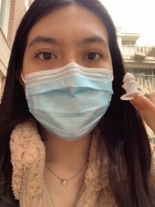 Selfie of Karla Cordova holding a 3D-game piece with a surgical mask on. 