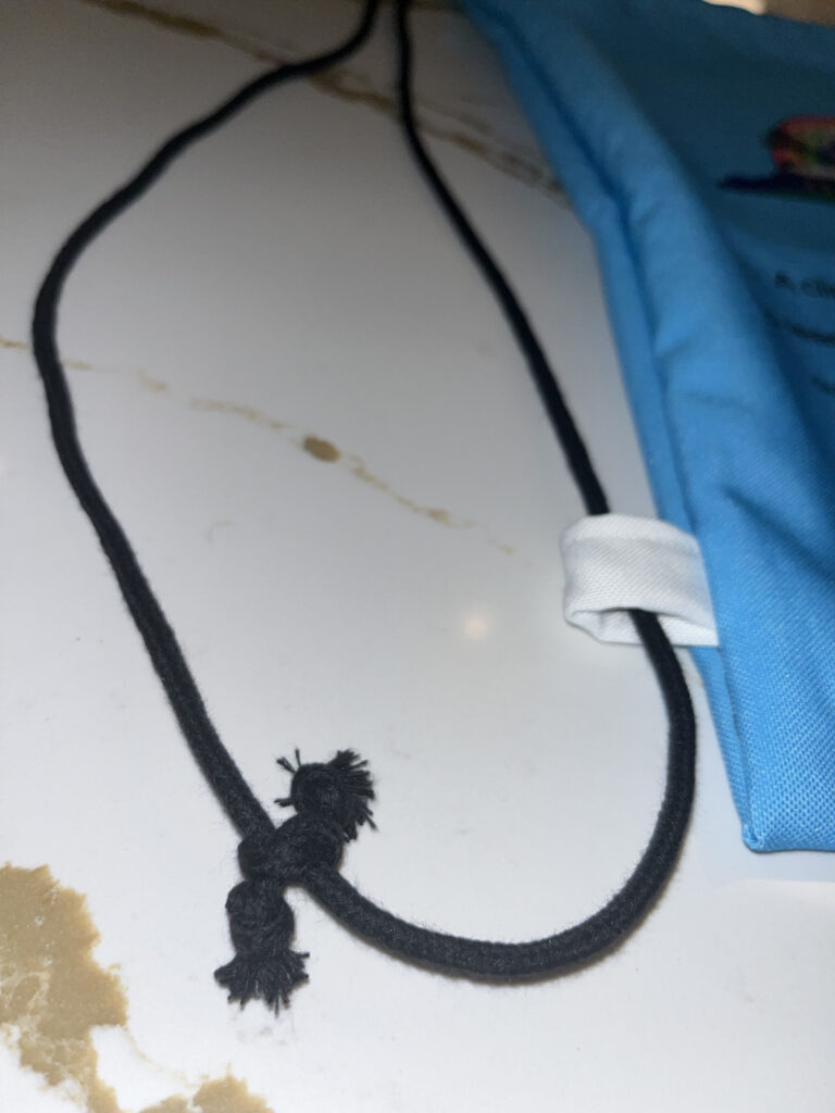 Black cord connected to Climatopia bag tied together and through white loop