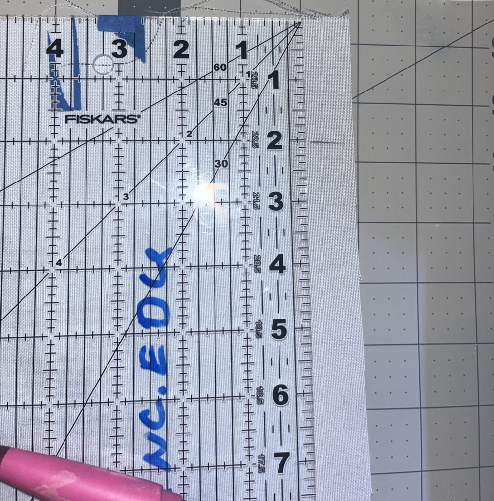 A clear ruler laid on the back of the drawstring bag.