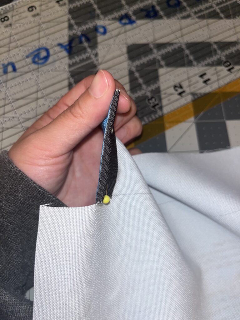 Hand holding the corner of an inside out Climatopia drawstring bag with a pin in it
