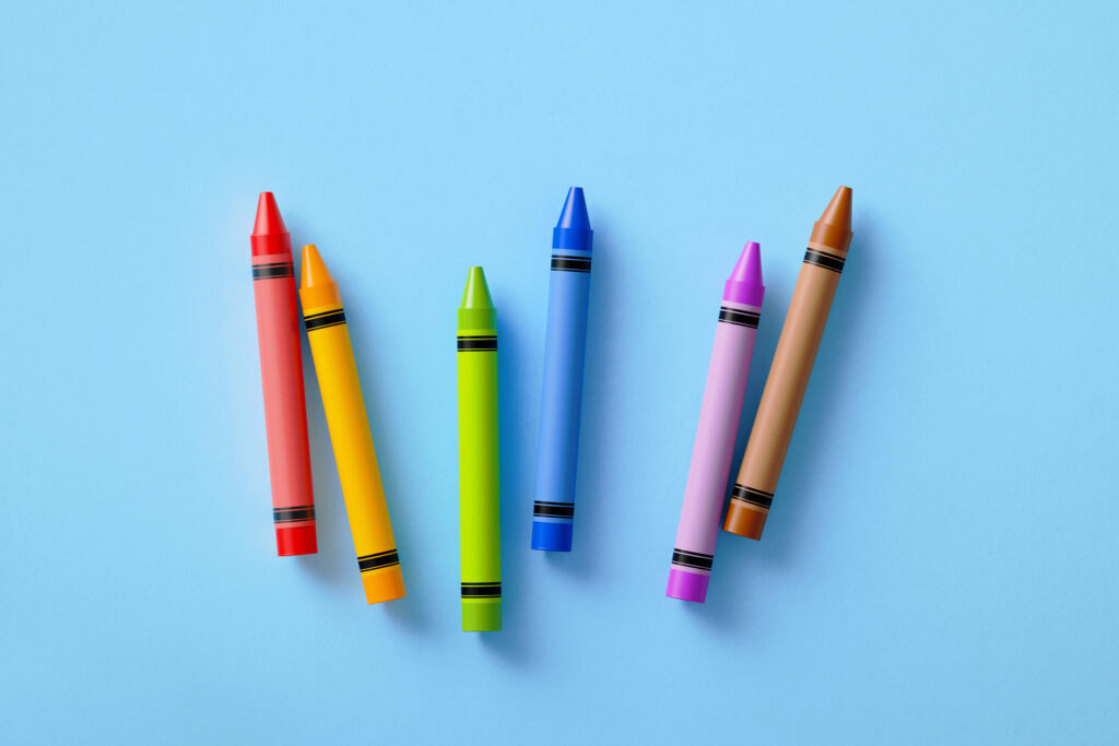 Different colored crayons laying on a blue background