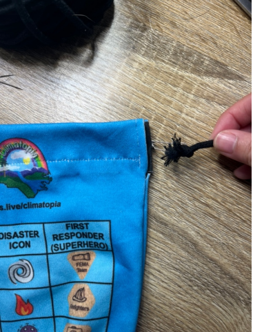 Clipping the black cord to a bobby pin on the top right side of the game piece bag. 