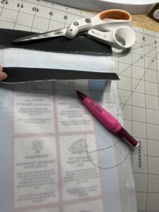 Pink pen and scissors laying on top of inside out climatopia fabric