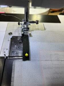 Inside out fabric in sewing machine with yellow pin holding together fabric