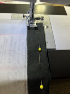 Inside out fabric in sewing machine with yellow pin holding together fabric