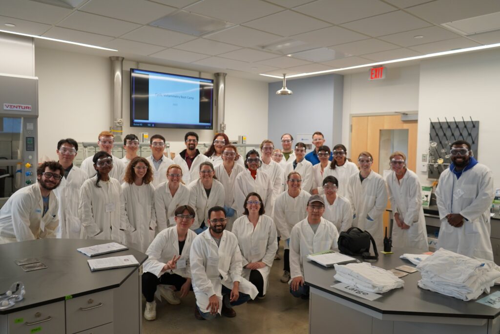 Photo of a group of people in lab coats located within a chemistry lab.