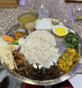A full Thali plate with rice, lentils, veggies, ghee, aachar, and dahi