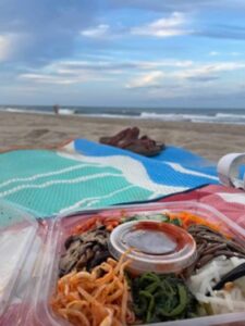 Bibimbap food on a towel with the beach in the background