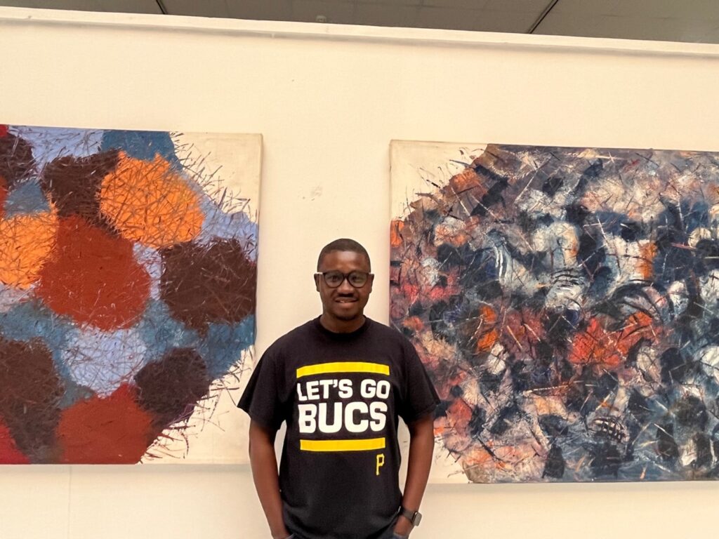 Simon standing in front of two paintings