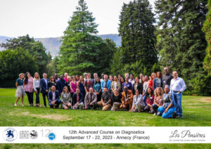 The ACDx group participants pose for a picture outside in front of tall green trees 