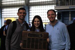 Three UNCBAA leadership members standing together with the scholarship plaque.