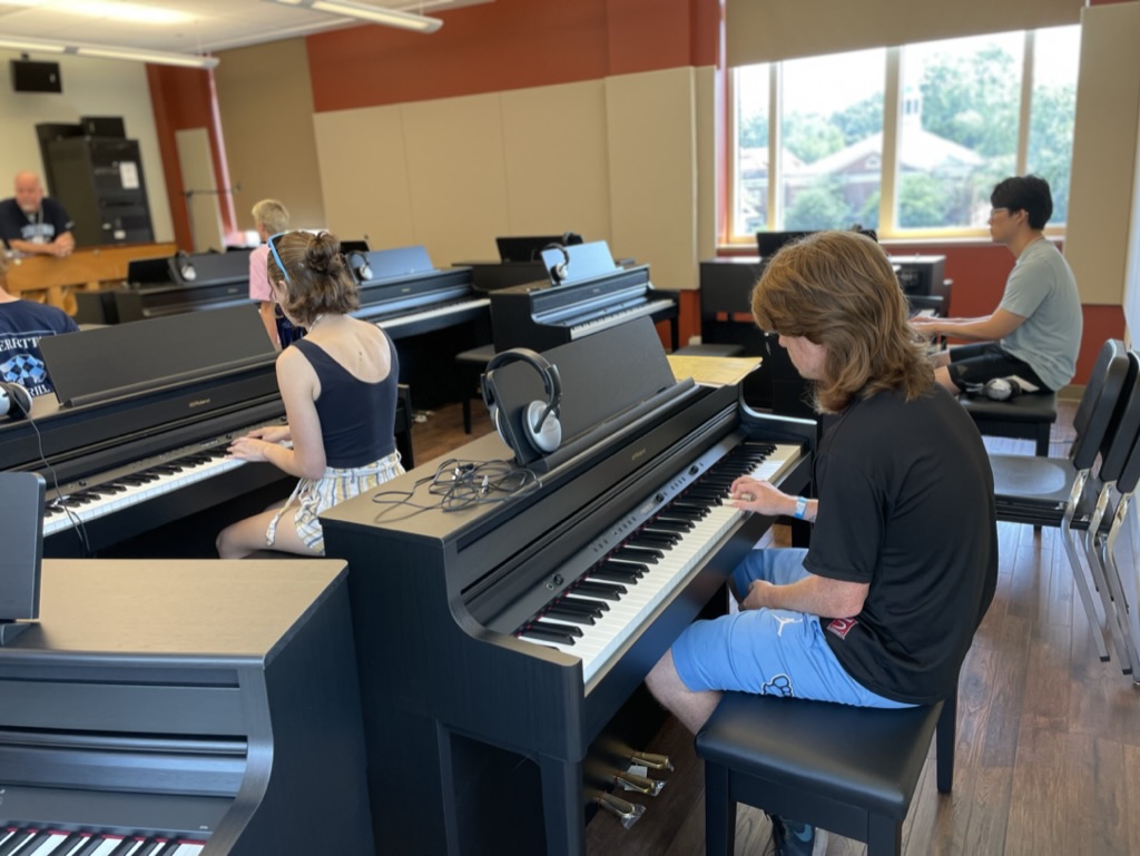 Students sit at keyboard in the piano lab and work on playing jazz chords.