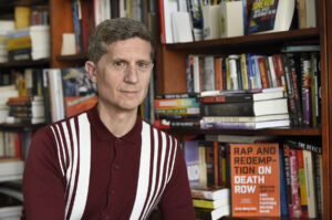 Mark Katz in front of a bookshelf with his new book prominently displayed beside him.